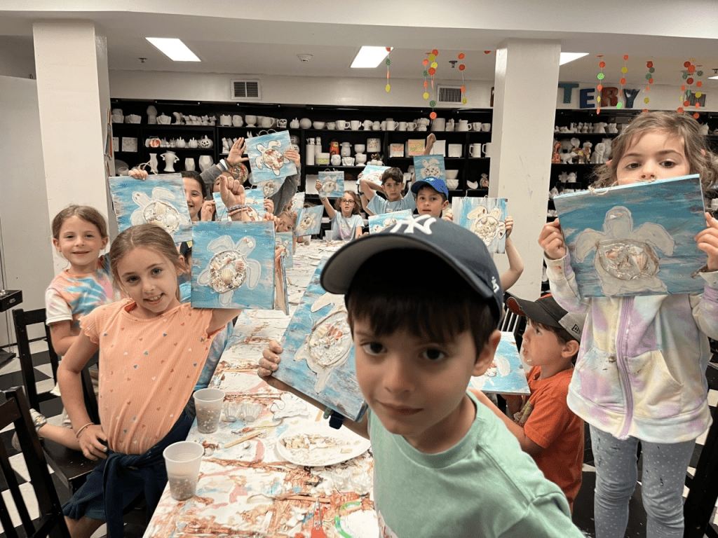 Proud children showcasing finished canvas paintings from an art class in Englewood, NJ